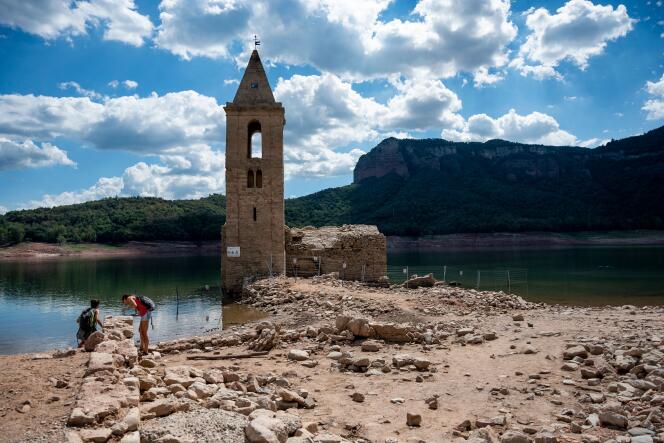 People stand in front of the ruins of the church of Sant Roma de Sau, at the swamp of Sau, located in Vilanova de Sau,  province of Girona in Catalonia on August 23, 2022.  