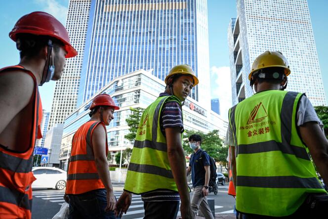 Des ouvriers du bâtiment traversent une route à Shenzhen, dans la province chinoise du Guangdong (sud), le 20 juillet 2022.