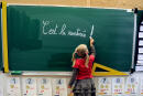 (FILES) In this file photograph taken on August 28, 2012, a young student writes on the blackboard "C'est la rentrée" (Its the Start of the school year) at the school Jules Ferry in Bethune, northern France, a few days ahead of the start of classes in France - known as "rentree des classes" in French.. - Minister of Education Pap Ndiaye's promised on August 26, 2022 - that a competition would be held for contract teachers, those who make up for the lack of teachers - in "a context of unprecedented tension for the recruitment of teachers". Pupils are scheduled to return to schools across France on September 1, 2022. (Photo by Denis CHARLET / AFP)