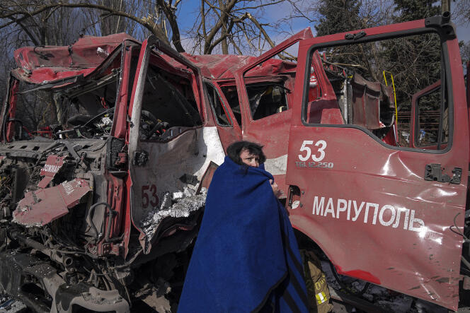 A woman stands in front of a fire truck that was destroyed by missiles.  Mariupol, Ukraine, March 10, 2022.