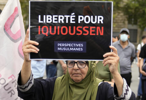 A woman holds a placard reading "Freedom for Iquioussen" during a gathering to support Imam Hassan Iquioussen at Place de la Republique in Paris, France, Saturday, Sept. 3, 2022. Iquioussen, accused by the French government of hate speech, was to be expelled to Morocco following a decision earlier this week from France's top administrative court, but police was unable to find him at his home in northern France. (AP Photo/Francois Mori)