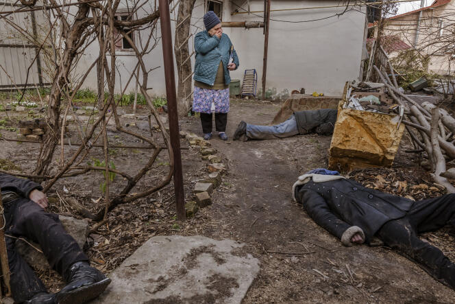 Tatiana Petrovna, 72, near the bodies of her friend Serhi, her brother-in-law Roman and a stranger, outside their home.  Russian forces are responsible for the murder of these three civilians.  Serhi had stayed behind to take care of his two dogs, who were also shot.  Boucha (Ukraine), April 4, 2022.