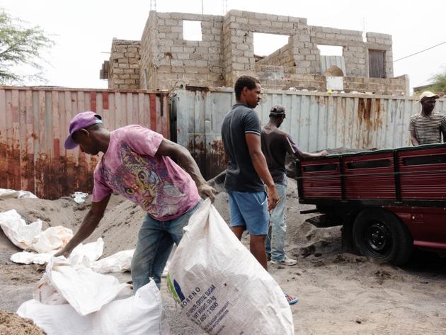A l’abri des regards, sur un parking, des ouvriers remplissent des sacs de sable de 50 kilos qui seront vendus à des particuliers, à Praia, la capitale, le 13 juin 2022.