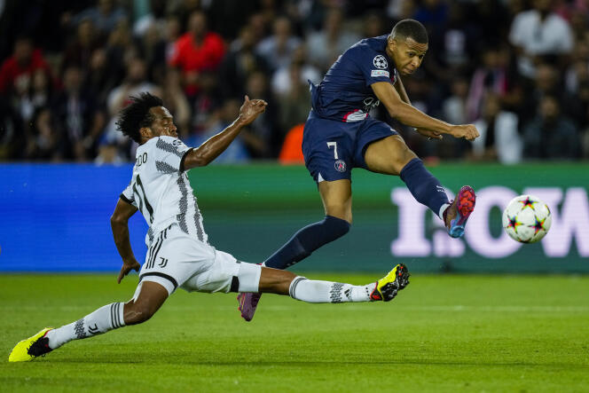 Juventus' Juan Cuadrado, left, duels for the ball with PSG's Kylian Mbappe during the Champions League soccer match Group H at the Parc des Princes stadium, in Paris, Tuesday, Sept. 6, 2022.