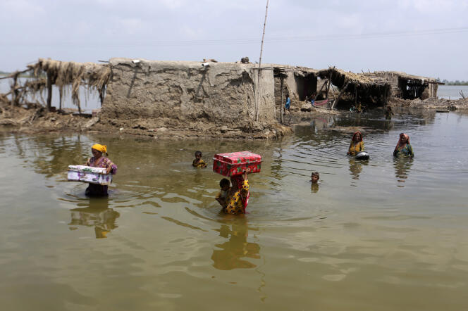 Des femmes transportent des biens récupérés de leur maison inondée au Pakistan, en septembre 2022.