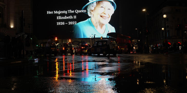 The image of Queen Elizabeth II is projected onto a large screen and reflected in a rainy street at Piccadilly Circus, in London, Thursday, Sept. 8, 2022. Queen Elizabeth II, Britain's longest-reigning monarch and a rock of stability across much of a turbulent century, died Thursday after 70 years on the throne. She was 96. (AP Photo/Alberto Pezzali)