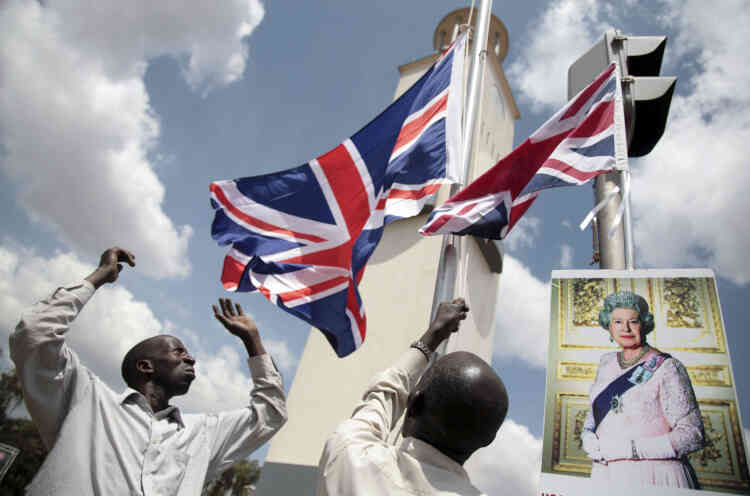 Gli ugandesi alzano bandiere britanniche davanti a un ritratto di Elisabetta II durante una visita della regina a Kampala per un vertice del Commonwealth nel novembre 2007.