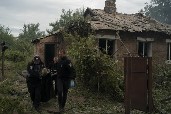 Des policiers portent un sac contenant un corps retrouvé dans une maison après une attaque russe dans la région de Pokrovsk, le 11 septembre 2022.