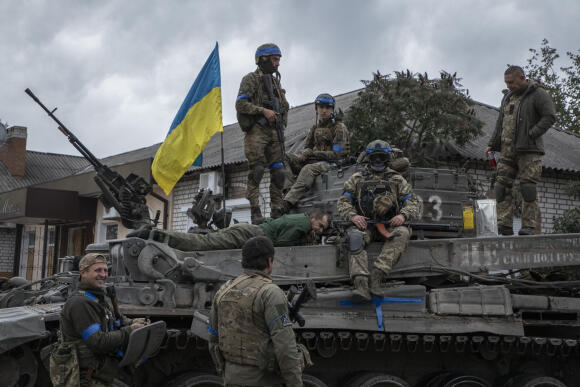 Un soldat russe, fait prisonnier, est maintenu allongé sur un tank avec des soldats ukrainiens, à Izioum.