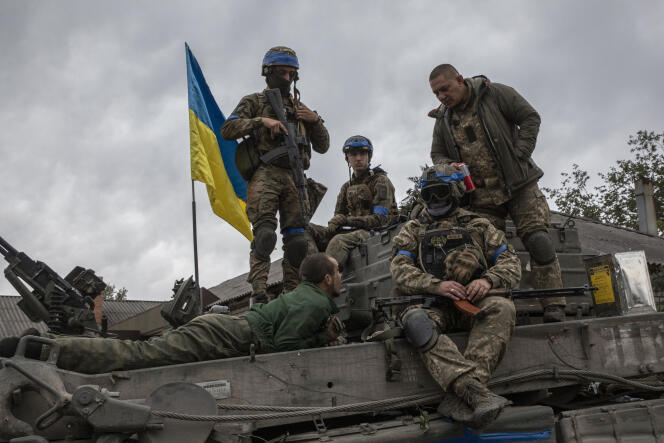 Un soldat russe fait prisonnier est allongé sur un tank, entouré de soldats ukrainiens, à Izioum (Ukraine), le 11 septembre 2022.
