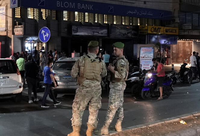 Lebanese soldiers in front of a branch of Blom Bank, stopped by one of its customers in Beirut, September 16, 2022.
