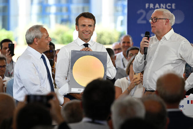 Le président français Emmanuel Macron, en compagnie du président de Global Foundries Thomas Caulfield (gauche), pose avec une plaquette de silicium, alors qu’il écoute le discours du président de STMicroelectronics Jean-Marc Chery (droite), lors d’une visite chez STMicroelectronics, à Crolles (Isère), le 12 juillet 2022. 