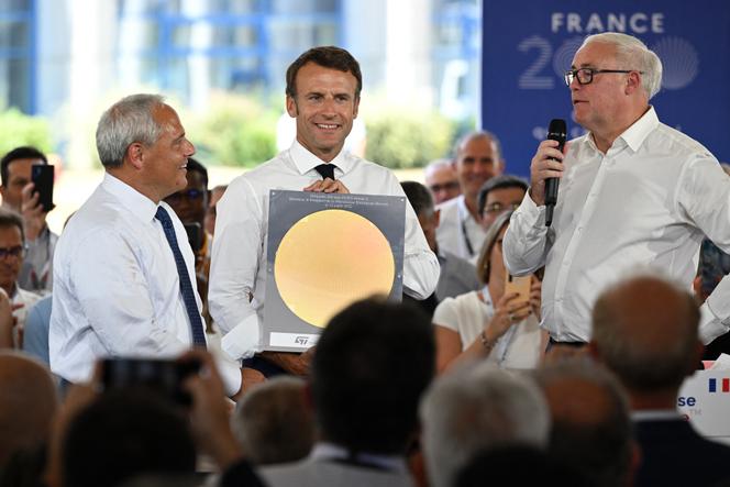 Le président français Emmanuel Macron, en compagnie du président de Global Foundries Thomas Caulfield (gauche), pose avec une plaquette de silicium, alors qu’il écoute le discours du président de STMicroelectronics Jean-Marc Chery (droite), lors d’une visite chez STMicroelectronics, à Crolles (Isère), le 12 juillet 2022. 