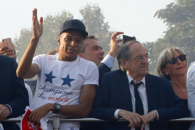 El delantero de Les Bleus, Kylian Mbappé, y el presidente de la Federación Francesa de Fútbol, ​​Noël Le Graët, saludan a la multitud que ha venido a celebrar en los Campos Elíseos, en París, la victoria de la selección francesa en el Mundial de Rusia, el 16 de julio. , 2018.