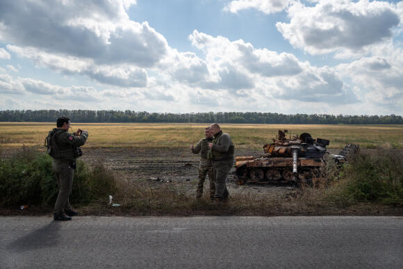 Des militaires posent devant un char russe calciné, sur la route entre Kharkiv et Koupiansk, en Ukraine, le 18 septembre 2022.