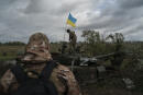 Un membre de la garde nationale ukrainienne se tient sur un char russe détruit dans la région frontalière de Kharkiv, le 19 septembre 2022.