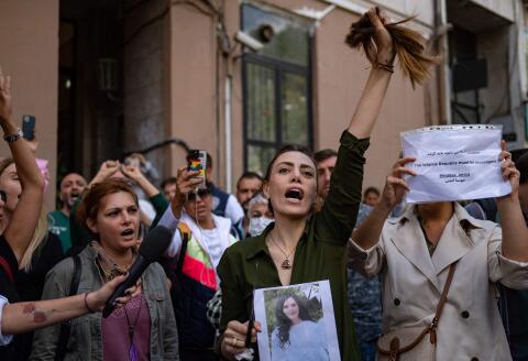 TOPSHOT - Nasibe Samsaei, an Iranian woman living in Turkey, holds up her ponytail after cutting it off with scissors, during a protest outside the Iranian consulate in Istanbul on September 21, 2022, following the death of an Iranian woman after her arrest by the country's morality police in Tehran. Mahsa Amini, 22, was on a visit with her family to the Iranian capital Tehran, when she was detained on September 13, 2022, by the police unit responsible for enforcing Iran's strict dress code for women, including the wearing of the headscarf in public. She was declared dead on September 16, 2022 by state television after having spent three days in a coma. (Photo by Yasin AKGUL / AFP)