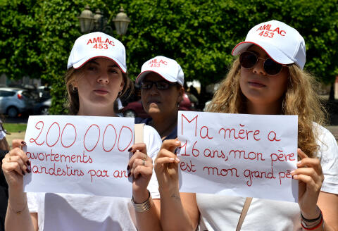 Demonstrators hold placards near the parliament of the Moroccan capital Rabat on June 25, 2019, to protest against an abortion law. - "Article 453", refers to a law which punishes the voluntary termination of pregnancy (abortion) with six months to five years of imprisonment except when the health of the mother is in danger.Protesters today led an action to demand the easing of a law they believe encourages clandestine abortions and child abandonment. (Photo by AFP)