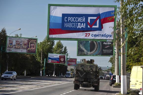 Un véhicule militaire russe passe sous un panneau publicitaire où est écrit : « Avec la Russie, pour toujours. Le 27 septembre », à Louhansk dans l’est de l’Ukraine. Le 22 septembre 2022.