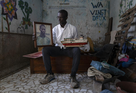 Le 21 septembre 2022, Ziguinchor, Senegal.
Elie Diatta pose avec une maquette du bateau le Joola et une photo de son frère Michel dans son ancienne chambre dans leur maison. Michel a disparu lors du naufrage du bateau le Joola en 2002 ©SYLVAIN CHERKAOUI POUR LE MONDE