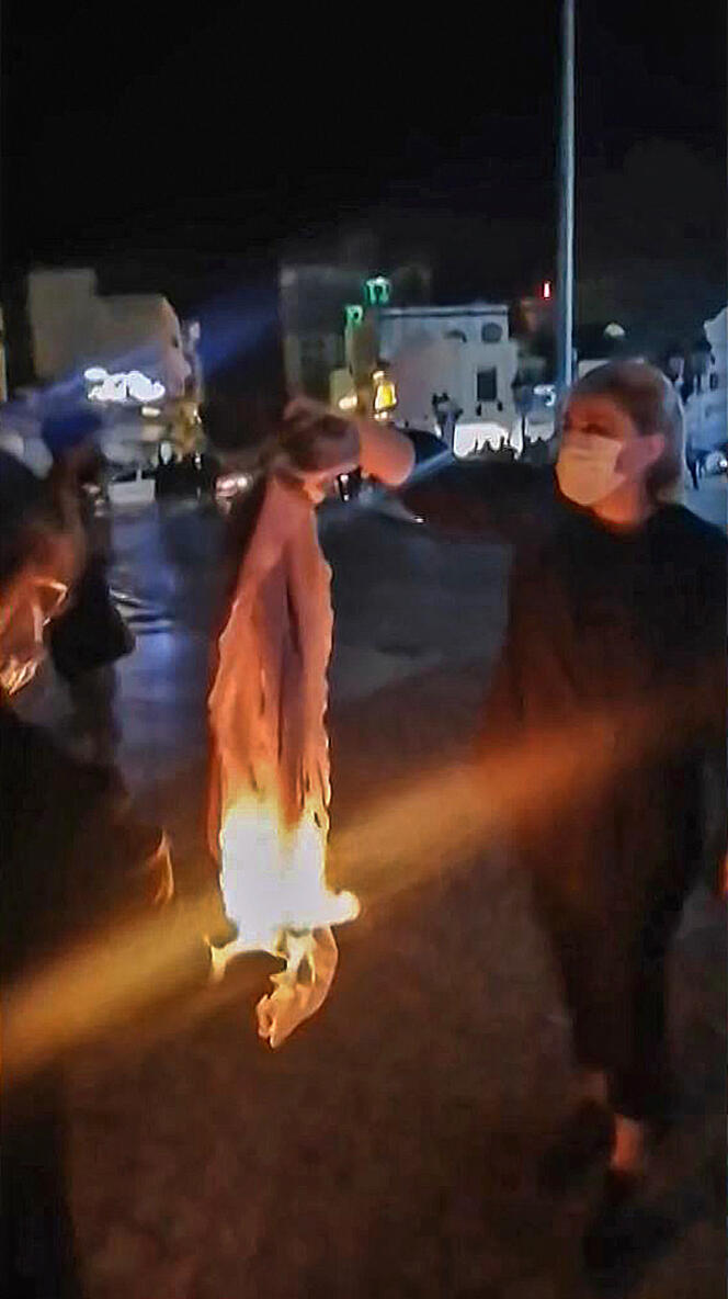 Screen capture from a video showing an Iranian protester burning her headscarf, in Buchehr, September 25, 2022. 