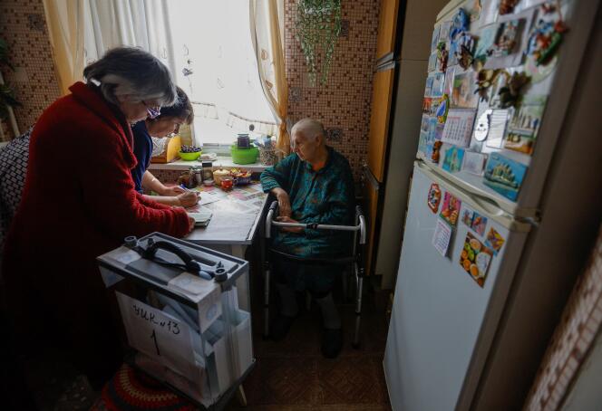 Des déléguées rendent visite à une femme de 90 ans pour obtenir son vote lors du « référendum » d’annexion, à Marioupol, ville ukrainienne occupée par les Russes, le 25 septembre 2022.