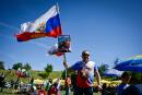 A man poses for a picture with a Russian national flag and a picture of the Russian President Vladimir Putin, during the annual "Russophiles meet", near the central Bulgarian town of Kalofer, on September 25, 2022. Russian songs, red flags and t-shirts bearing the image of Vladimir Putin: the war in Ukraine has not shaken the convictions of Bulgarian Russophiles, who gathered on Sunday in a festive atmosphere. (Photo by Nikolay DOYCHINOV / AFP)