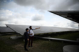 Two men look at the Labarde solar farm in Bordeaux southwestern France on May 12, 2022. - The solar farm of 140,000 solar panels is located on a former landfill and is the largest urban solar farm in Europe. (Photo by Philippe LOPEZ / AFP)