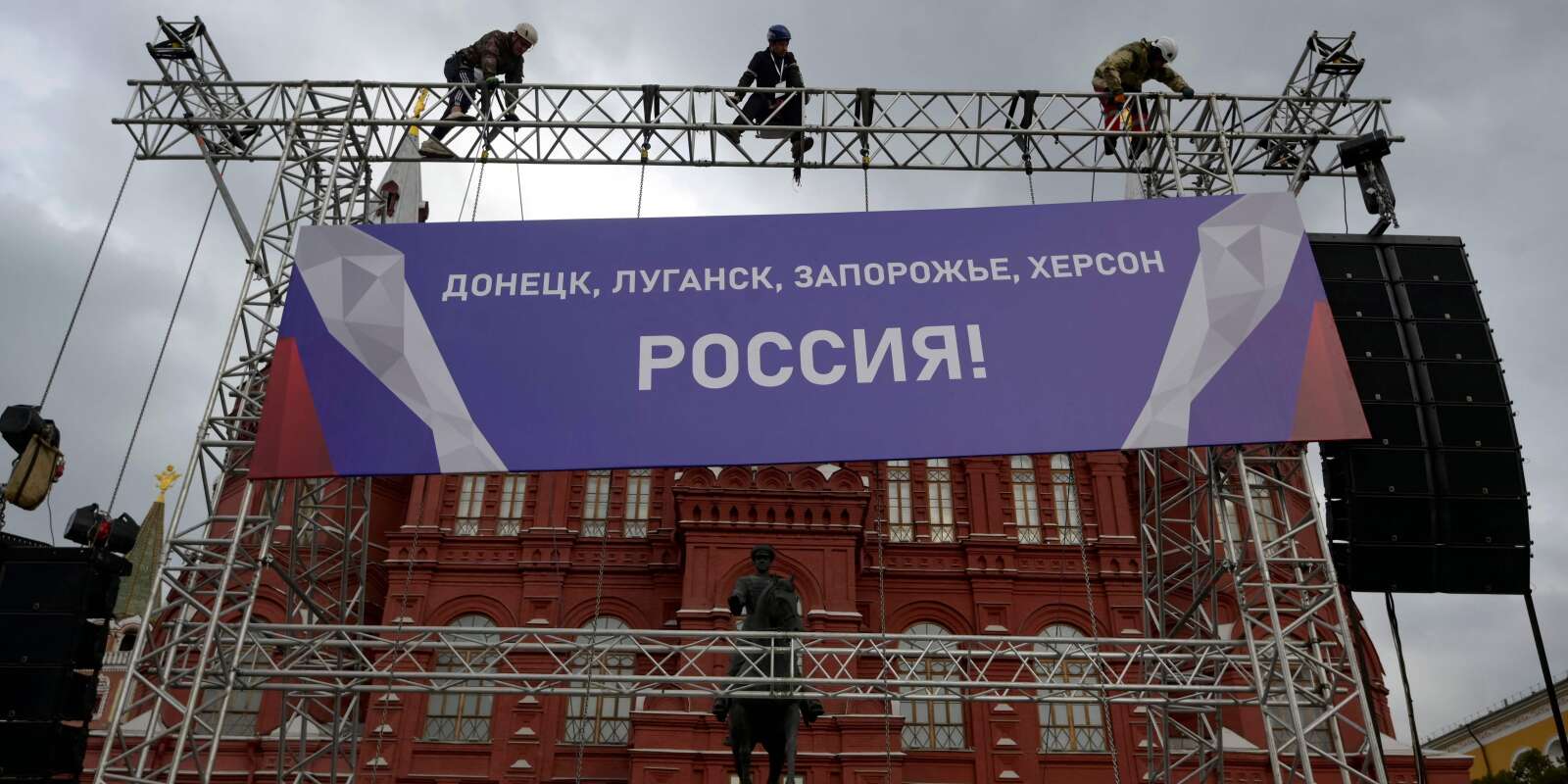 Des ouvrier installent une banderole indiquant « Donetsk, Louhansk, Zaporijiaa, Kherson - Russie ! » au sommet d’une construction d’échaffaudages installés sur la Place Rouge de Moscou, le 29 septembre 2022.