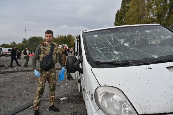 Un officier de police se tient à côté d’une camionnette endommagée par un tir de missile, à Zaporijia, le 30 septembre 2022.