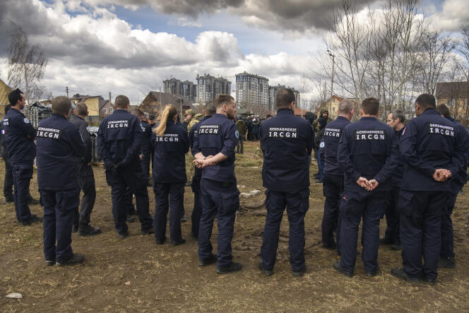 French forensics investigators, who arrived to Ukraine for the investigation of war crimes amid Russia's invasion, stand next to a mass grave in Bucha, Kyiv area, Ukraine, April 12, 2022.