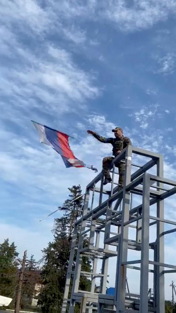 Un soldat ukrainien décroche un drapeau russe hissé sur un monument à Lyman, en Ukraine, dans cette capture d’écran obtenue à partir d’une vidéo publiée sur les médias sociaux, le 1er octobre 2022.