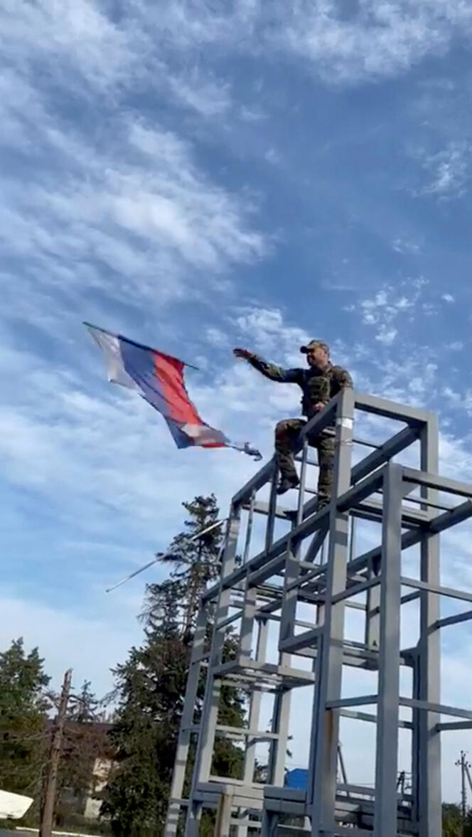 A Ukrainian soldier takes down a Russian flag hoisted on a monument in Lyman, Ukraine. Screenshot of a video posted on social networks, October 1, 2022.