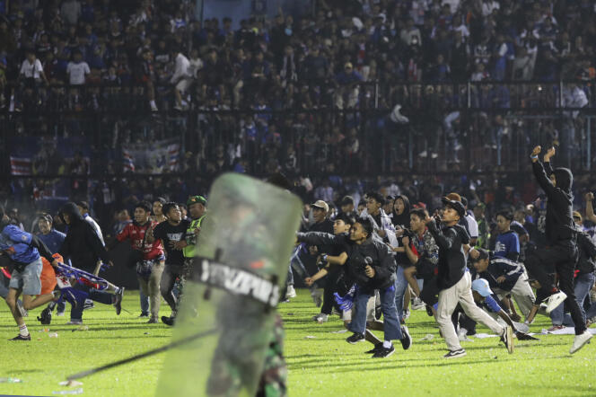 Fans crowd the pitch at Kanjuruhan Stadium in Malang, East Java, Indonesia on October 1, 2022. 