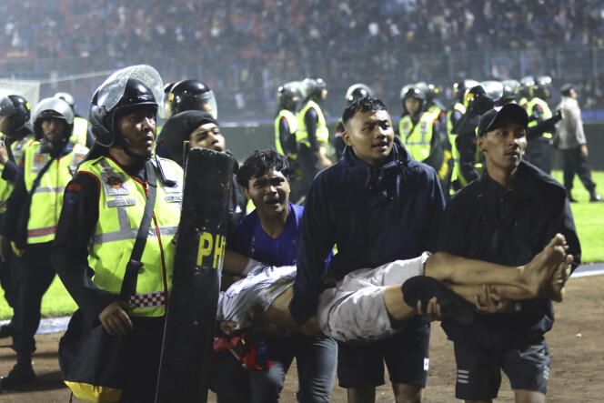 Des supporteurs portent un blessé lors de confrontations entre supporteurs dans le stade Kanjuruhan, à Malang, dans l’est de Java, en Indonésie, le 1er octobre 2022. 