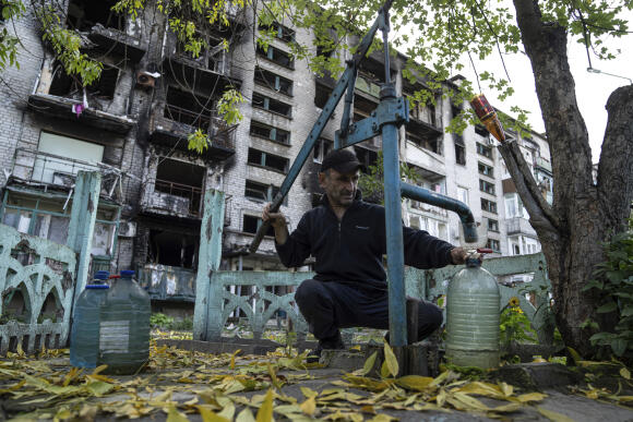 Un homme utilise une pompe à eau devant un immeuble d’habitations détruit par les bombardements, à Lyman, le 3 octobre 2022.