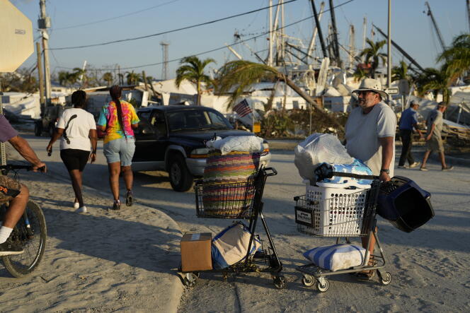 Un residente espera con sus pertenencias rescatadas de su hogar en ruinas después de evacuar Estero Island en Fort Myers Beach, Florida, el 1 de octubre de 2022, tres días después del paso del huracán Ian.