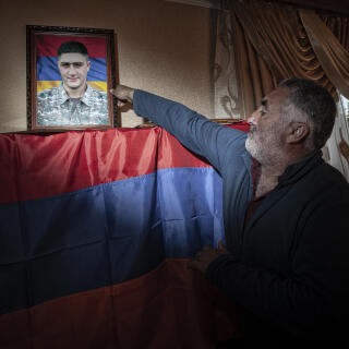 2022.09.28/ARMENIA/Litchk village/Father Gvido Markarian puts a photograph of his dead son on a shelf decorated with an Armenian flag.