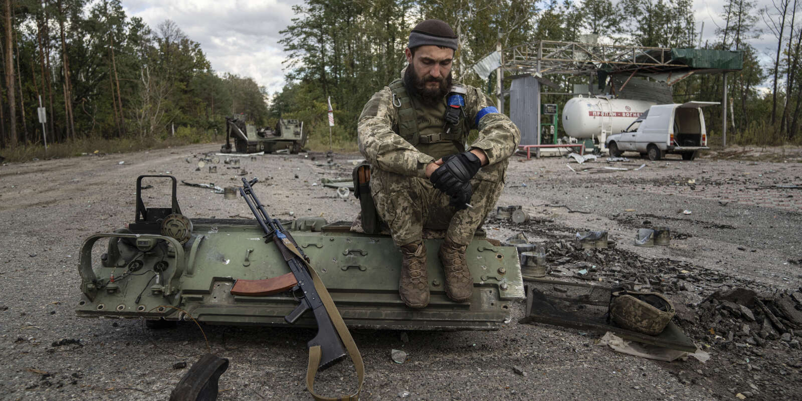 Un militaire ukrainien assis sur un morceau de véhicule blindé, aux abords de la ville de Lyman, en Ukraine. Le 3 octobre 2022.