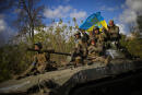 Ukrainian soldiers sit on an armoured vehicle as they drive on a road between Izium and Lyman in Ukraine, Tuesday Oct. 4, 2022. (AP Photo/Francisco Seco)