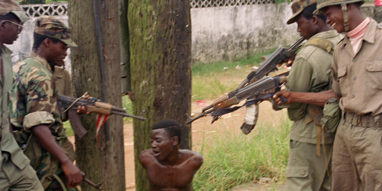 Members of the anti-Taylor militia ULIMO, tease a suspected NPFL soldier with a mock execution on the outskirts of Monrovia, Liberia, Nov. 2, 1992. Since ULIMO were allowed to roam freely in Monrovia two weeks ago, there have been no reports of looting or harassment by the militia. (AP Photo/Hassan Amini)
