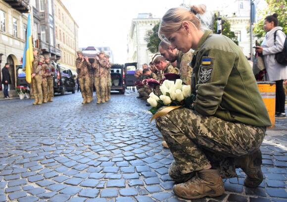 Ukrainian soldiers kneel as their comrades carry the coffins of Ukrainian soldiers killed in action during a funeral ceremony.  In Lviv, October 7, 2022.