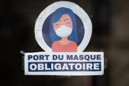Cette photo prise le 13 mars 2022 montre un autocollant indiquant « Le port du masque est obligatoire » sur la porte d’un magasin à Paris.