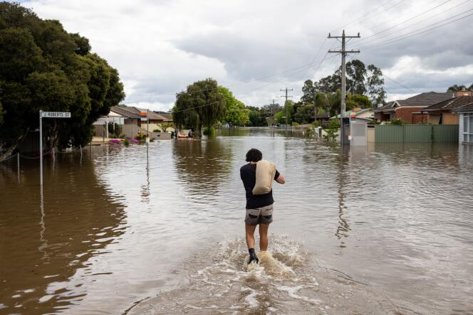 Sur ce cliché pris dimanche 16 octobre 2027, un résident transporte un sac de sable à travers la ville de Shepparton, en Australie, alors qu’elle est innondée.