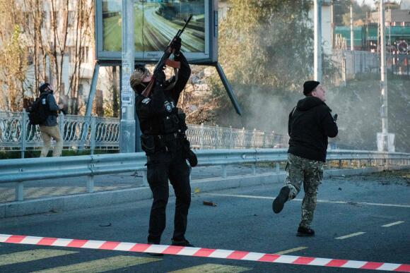 A police officer shoots a flying drone after attacks in kyiv on October 17, 2022.
