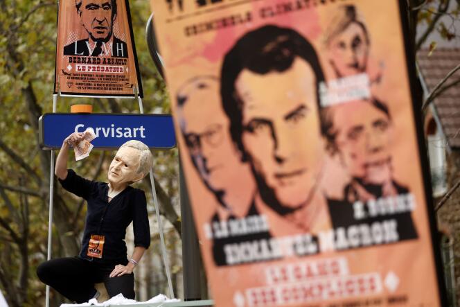 A protester wearing a mask depicting Bernard Arnault, chairman of LVMH Moet Hennessy Louis Vuitton, is seen next to a poster with a portrait of French President Emmanuel Macron during a demonstration in Paris as part of a nationwide day of strike and protests for higher wages and against requisitions at refineries in France, October 18, 2022.
