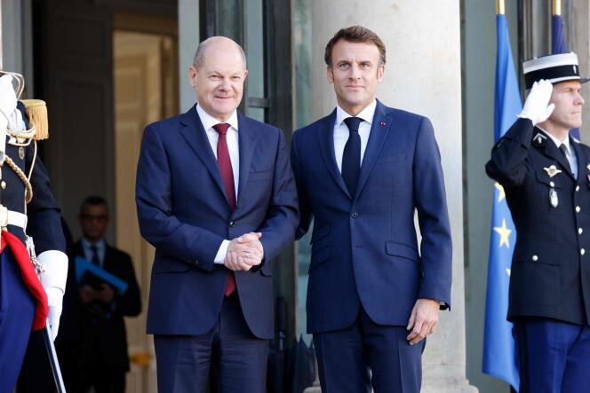 France's President Emmanuel Macron (R) and German Chancellor Olaf Scholz pose upon Scholz' arrival for a lunch at the presidential Elysee Palace in Paris on October 26, 2022.