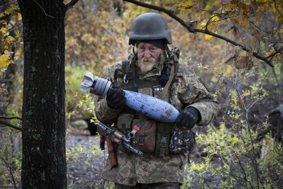 A Ukrainian soldier carries a shell with a written message to the Russian army.