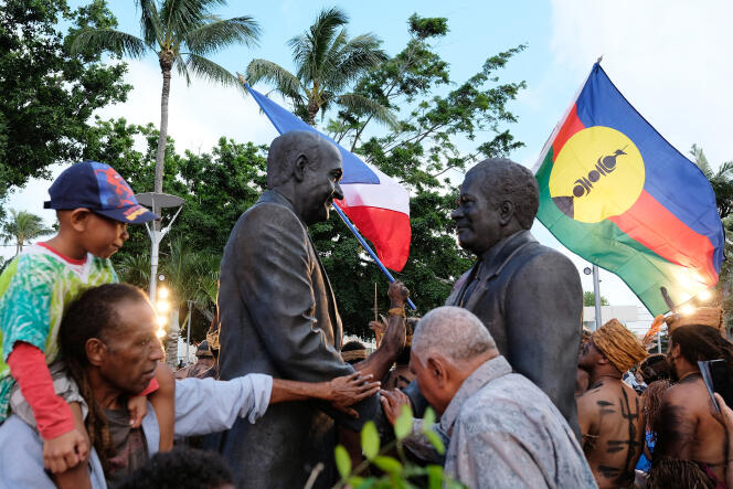Le public découvre une statue du leader anti-indépendantiste Jacques Lafleur serrant la main du chef du mouvement indépendantiste kanak Jean-Marie Tjibaou, lors de la signature des accords de Matignon, en juin 1988, lors de son inauguration à Nouméa, le 26 juin 2022.