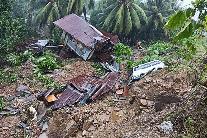 Des habitants se tiennent devant une maison effondrée après un glissement de terrain survenu en raison des fortes intempéries qui ont frappé le sud des Philippines, le vendredi 28 octobre 2022.